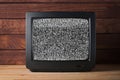 Old vintage TV set televisor on wooden table againt dark wooden wall background with no signal television grainy noise effect on Royalty Free Stock Photo