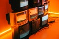 Old vintage tvs on a floor in a room with colored neon light