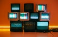 Old vintage tvs on a floor in a room with colored neon light