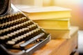 Old and vintage type writer machine and piles of books on wooden table - very selective focus. Royalty Free Stock Photo