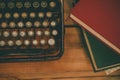 Old and vintage type writer machine and piles of books on wooden table - in vintage tone Royalty Free Stock Photo