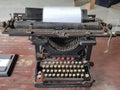 Old vintage typewriter with a blank sheet of paper inserted in wood background