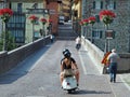 Old vintage Vespa and pedestrians cross the ancient Devil bridge, in the italian town of Cividale del Friuli, after the reopening.