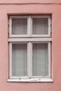 Old vintage window in a white wooden frame on a pink wall. Royalty Free Stock Photo