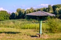 Old vintage wooden beach umbrella on abandoned, grassy and reed river beach on a sunny summer day Royalty Free Stock Photo