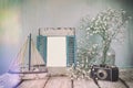 Old Vintage Wooden Frame, White Flowers, Photo Camera And Sailing Boat On Wooden Table. Vintage Filtered Image