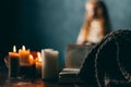 On the old vintage wooden table is a candlestick with candles. A red-haired girl in vintage clothes is sitting at the table, readi Royalty Free Stock Photo