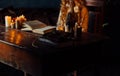 On the old vintage wooden table is a candlestick with candles. A red-haired girl in vintage clothes is sitting at the table, readi Royalty Free Stock Photo