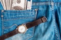 Old Vintage Wrist Watch on Blue Jeans Background and one hundred dollar bills in back pocket. Royalty Free Stock Photo