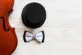 Old violin, cylinder hat and  bow tie on the white wooden background. Top view, close-up Royalty Free Stock Photo