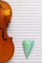 Old violin, narcissus and colorful heart figurine. Top view, close up, flat lay on white music paper background Royalty Free Stock Photo