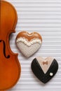 Old violin and two gingerbread heart shape figurines. Bride and groom. Top view, close up, flat lay on white music paper Royalty Free Stock Photo