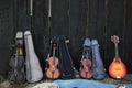 Old violins and a mandolin exposed in front of a black wooden fence