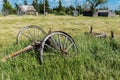 Old wagon wheels in an abandoned prairie yard with an old farmhouse, wind mill, and bins in the background