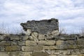 An old wall of an ancient stone building destroyed by time with dry grass on the background of a cloudy sky. Copy space. Royalty Free Stock Photo
