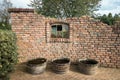 Old wall with broken window with three barrels filled with water