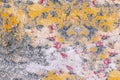 Old wall with crumbled paint: red, yellow, gray, white spots on the surface close-up. Royalty Free Stock Photo