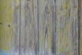 An old wall of dilapidated wooden planks, with stains and branches, with paint faded in the sun, yellow and blue Royalty Free Stock Photo