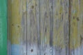 An old wall of dilapidated wooden planks, with stains and branches, with paint faded in the sun, yellow, green and blue Royalty Free Stock Photo