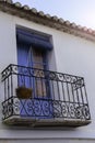 Old wall with peeling paint, scratched vintage plaster and a balcony with a blue door and blinds with wrought iron bars. Royalty Free Stock Photo