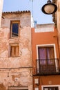 Old wall with peeling paint, scratched vintage plaster and a balcony with a rusty iron forged lattice.