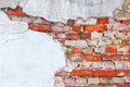 Old wall of red brick with loose plaster.