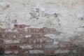 Old wall from a red brick plastered from above and covered with white paint. Plaster in places has disappeared Royalty Free Stock Photo