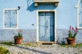 Old wall of a sunlit blue painted house with wooden door and balcony. Royalty Free Stock Photo