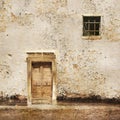 Old wall with wooden door and small window Royalty Free Stock Photo