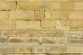 An old wall of yellowish Sandstone blocks. Blocks destroyed by time, eroded, ancient and old. Royalty Free Stock Photo