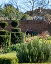 Walled garden at historic Eastcote House in the Borough of Hillingdon, London, UK. At back elederly couple sit on a bench.