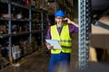 Warehouse worker talking on the phone holding clipboard in a large warehouse. Royalty Free Stock Photo