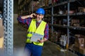 Warehouse worker talking on the phone holding clipboard in a large warehouse. Royalty Free Stock Photo