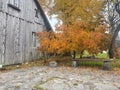 an old water column and a bench on the background of an autumn tree next to a wooden house