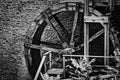 Old water mill wheel in front of stone wall. Black and white. Royalty Free Stock Photo