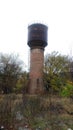 Old water station against the background of autumn foliage and t