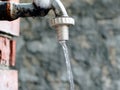 Old water tap with running water on bricked wall,  drinking water is flowing from the faucet, outdoor, close up Royalty Free Stock Photo