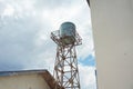 An old water tower with a tank whose color is starting to fade, with a rusty steel support Royalty Free Stock Photo