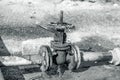 Old water valve. An rusty water valve in a puddle of flowing water. Large and rusty faulty leaking valve in close-up of an outdoor Royalty Free Stock Photo