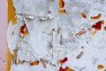 Old weather-aged wall pink, orange and red colors with crumbling plaster and scraps of paper on it