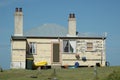 An old weatherboard house, against a blue sky.