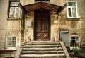 Old weathered brown entrance door under a hood with stairs Royalty Free Stock Photo