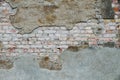 Old and weathered grungy broken brick wall from abandoned house partly covered with old cement with peeling background Royalty Free Stock Photo