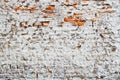 Old and weathered grungy red brick wall partly painted with white peeling paint and covered by old cement as texture background Royalty Free Stock Photo