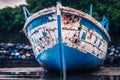 an old an weathered out boat lying in front of a pile of Tires Royalty Free Stock Photo