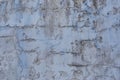 Old weathered painted wall background texture. White dirty peeled plaster wall with falling off flakes of paint Royalty Free Stock Photo