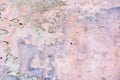 Old weathered painted wall background texture. White grey pink dirty peeled plaster wall with falling off flakes of Royalty Free Stock Photo