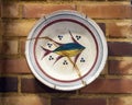 Old weathered plate with painted fish displayed on a brick wall in Aveiro, Portugal.