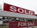 Old weathered sign sold over asking for sale in front of detached house in residential area. Royalty Free Stock Photo