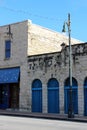 Old weathered stone building with bright blue iron gates and doorways, Austin, Texas, 2018